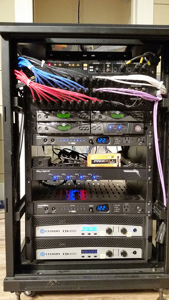 Audio equipment rack with Crown amplifiers, AKG wireless receivers, and patch cables