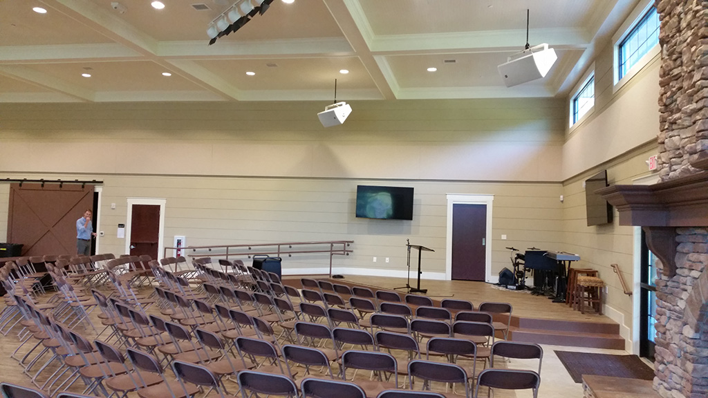 Cornerstone Prep Academy cafeteria with ceiling-mounted speakers, display, and stage area