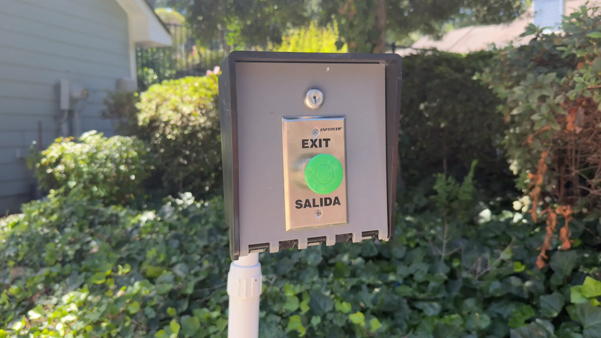 Pool gate exit button in a weather-protected enclosure at The Willows HOA