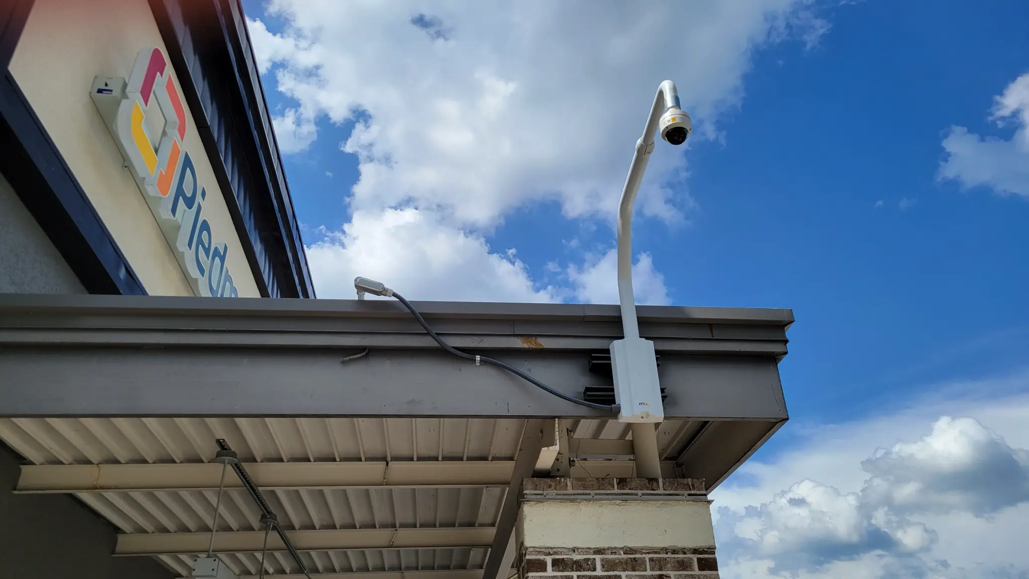 Security camera with mounting arm on Chamblee Plaza building exterior